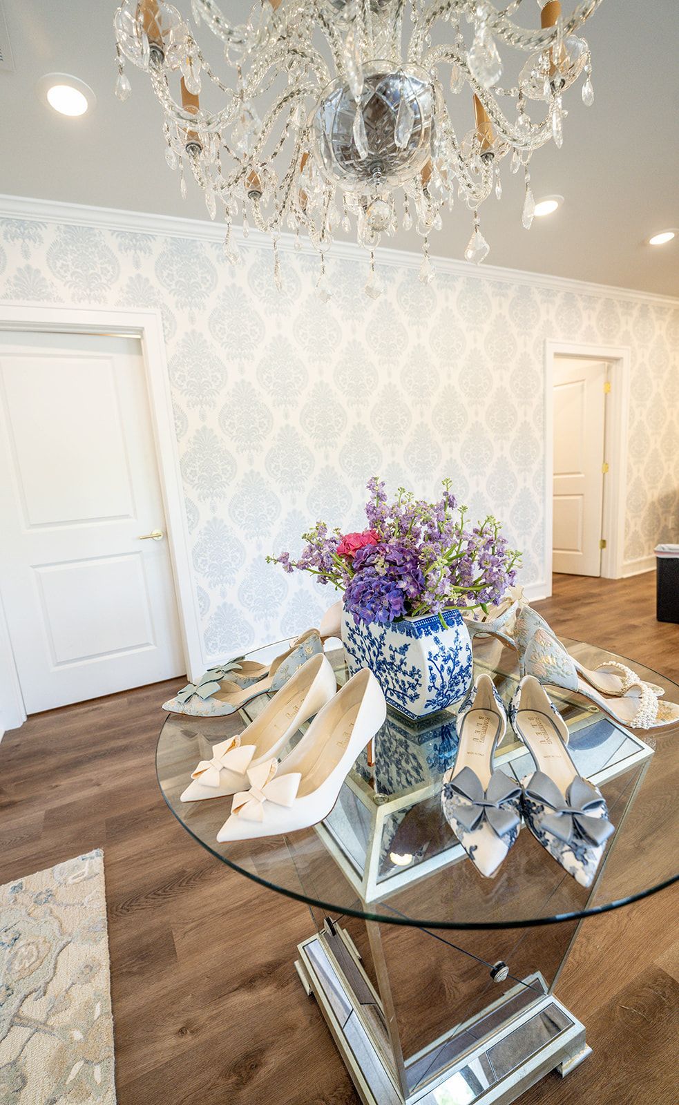 A table with a vase of flowers and shoes on it in a room with a chandelier.