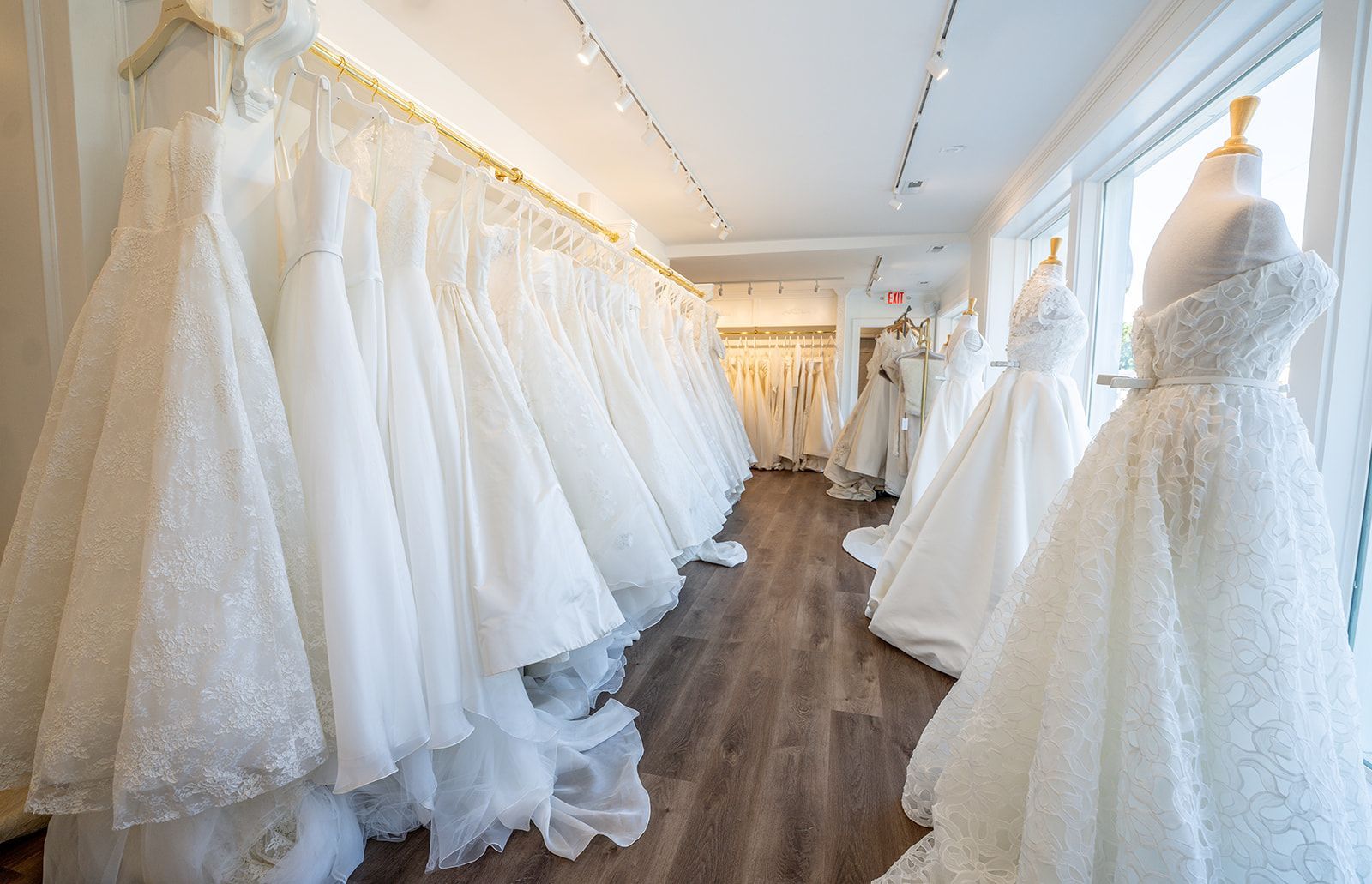 A room filled with lots of white wedding dresses on mannequins.