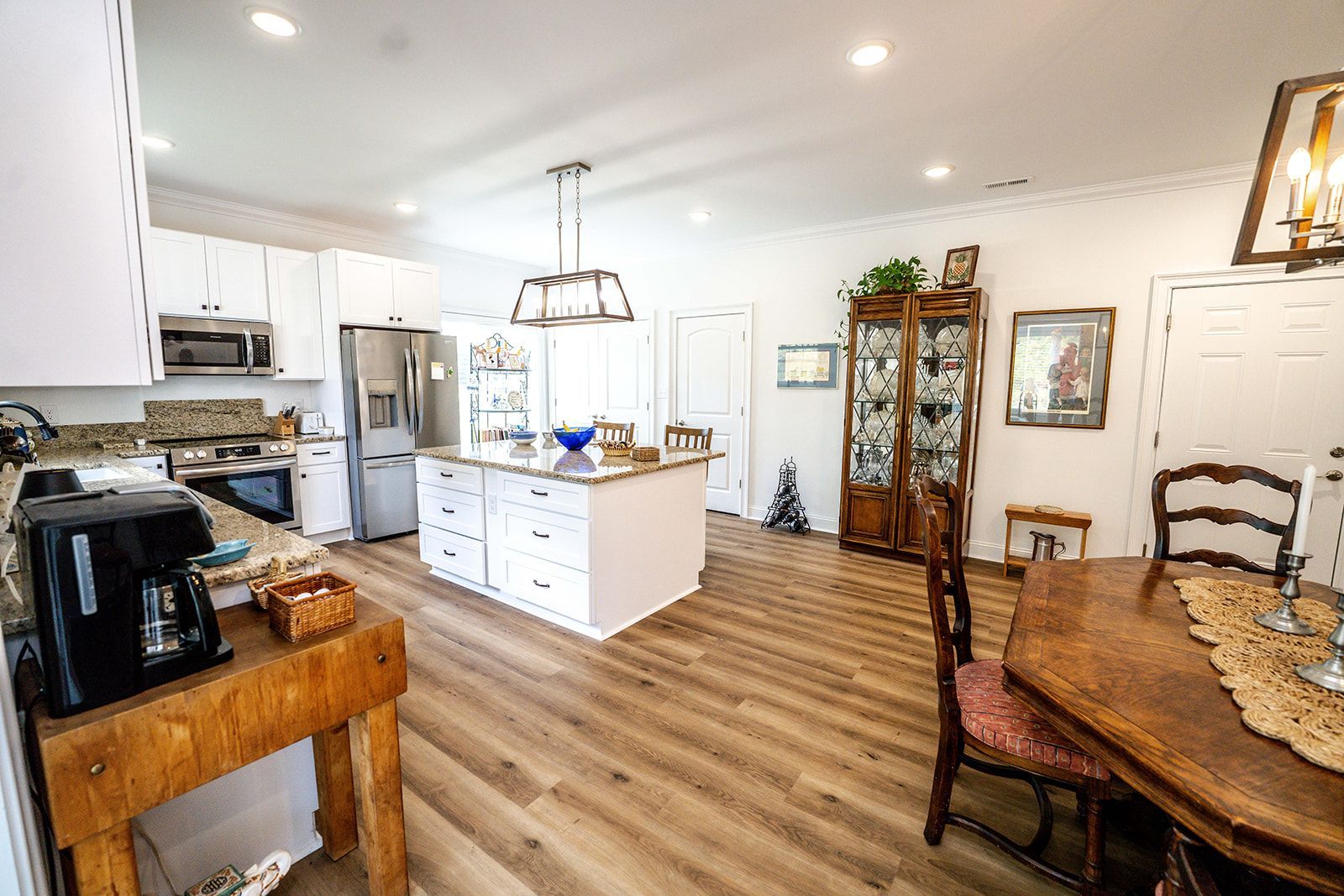 A kitchen and dining room in a house with hardwood floors and white cabinets.