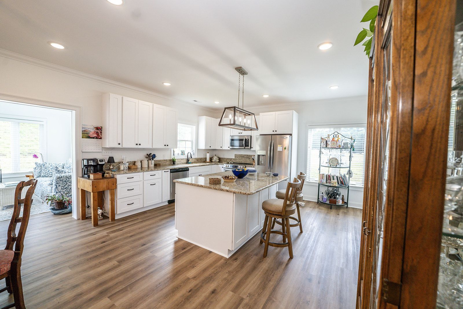 A kitchen with white cabinets , granite counter tops , stainless steel appliances and hardwood floors.