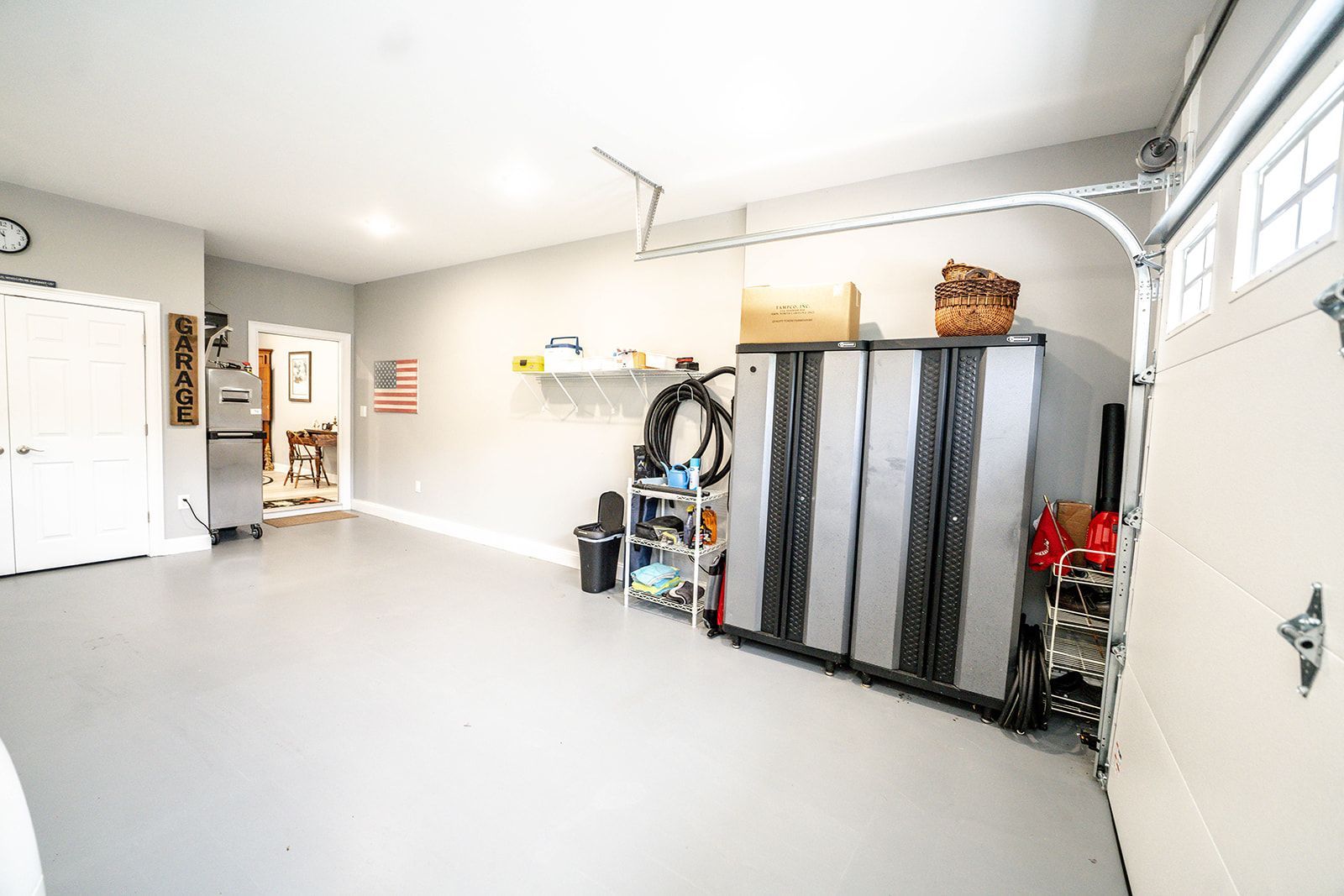 A garage with a garage door open and lots of storage space.
