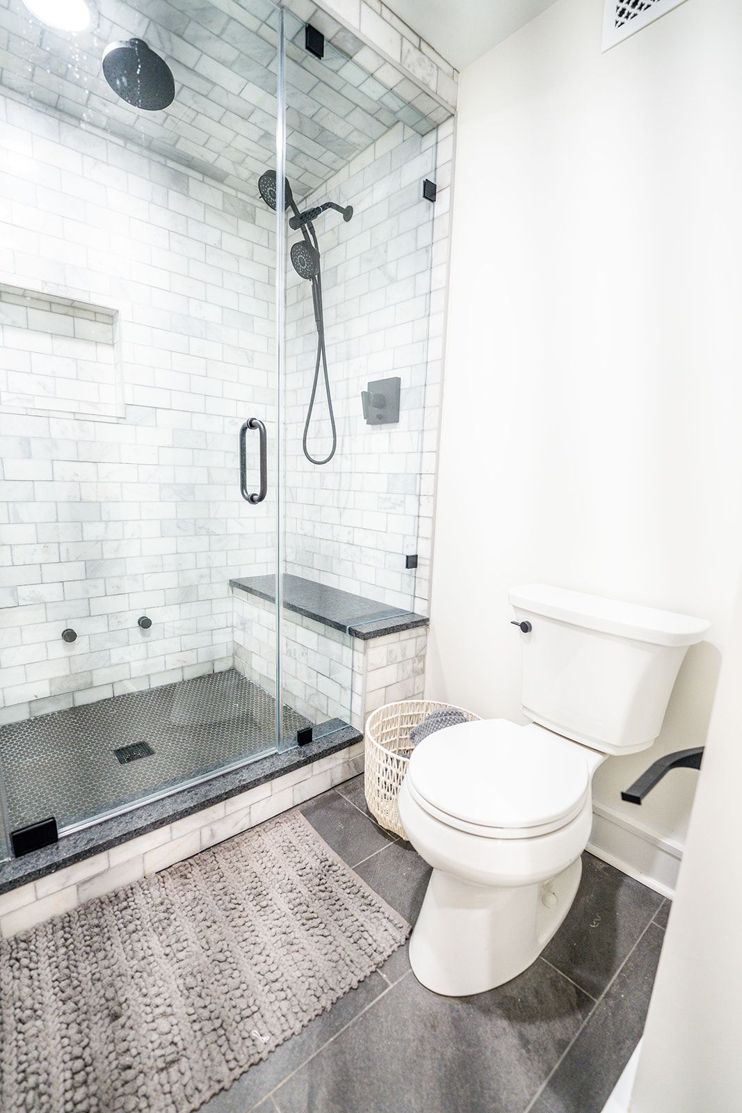 A bathroom with a toilet , shower , and rug.
