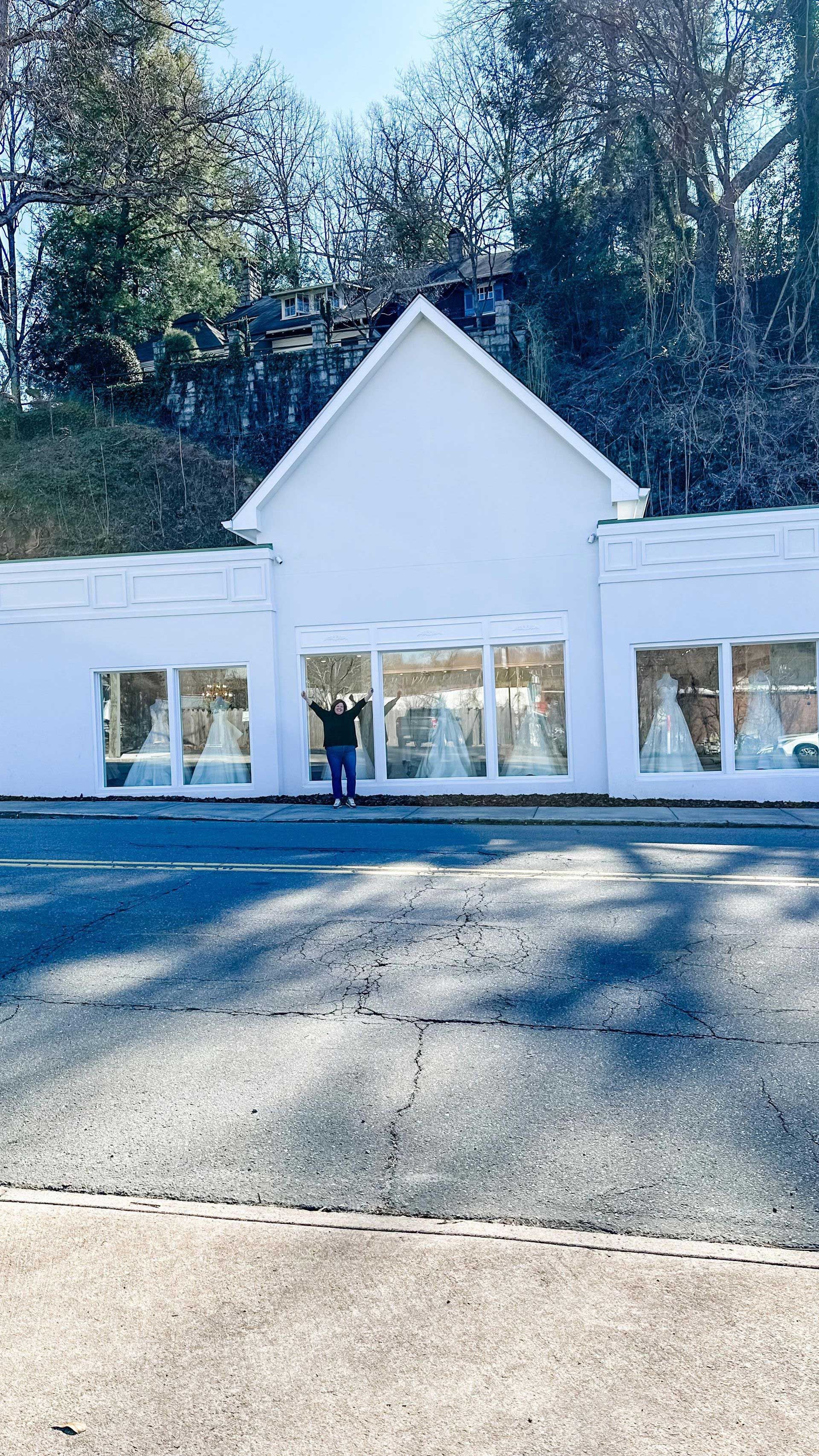 A woman is standing in front of a white building with a lot of windows.