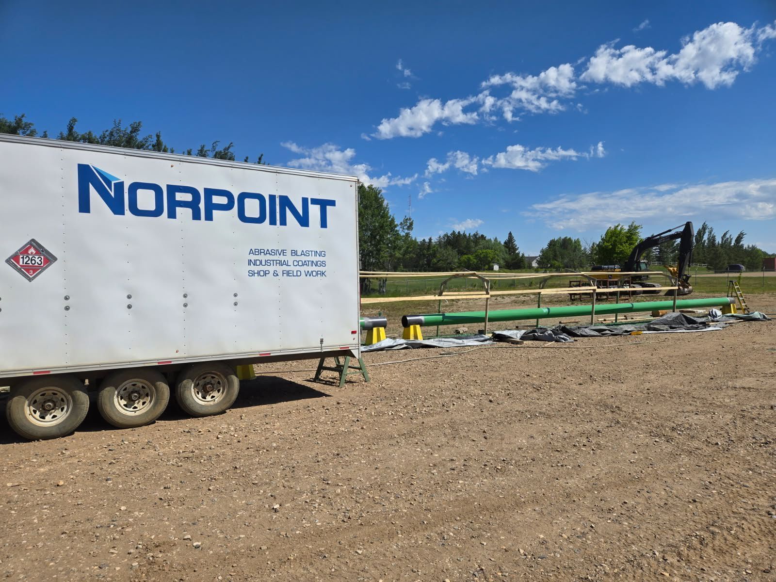 Norpoint field trailer at a coating job site with pipe preparation in progress
