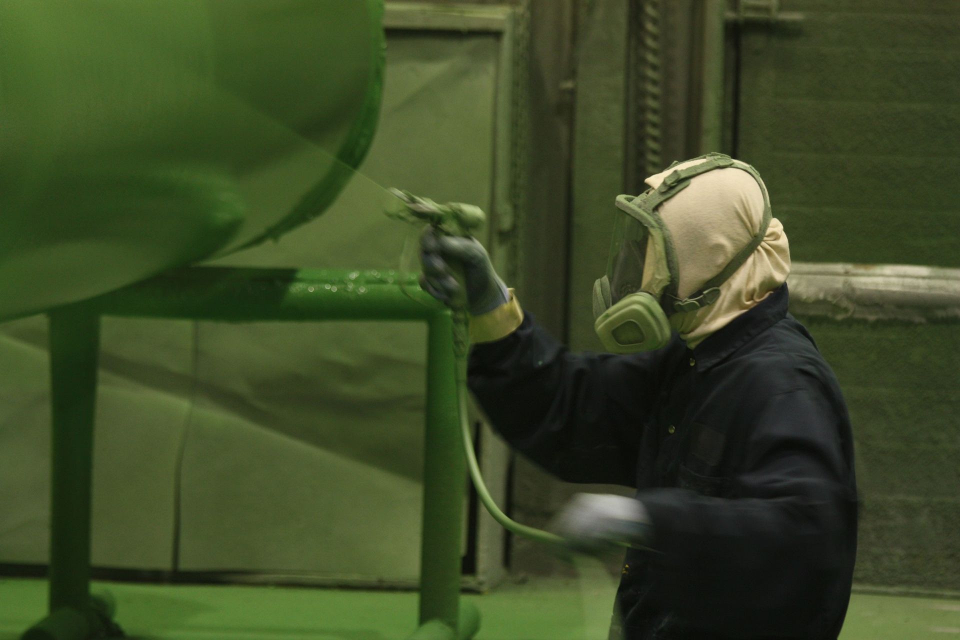 Technician performing precision blast cleaning and coating using industrial spray equipment