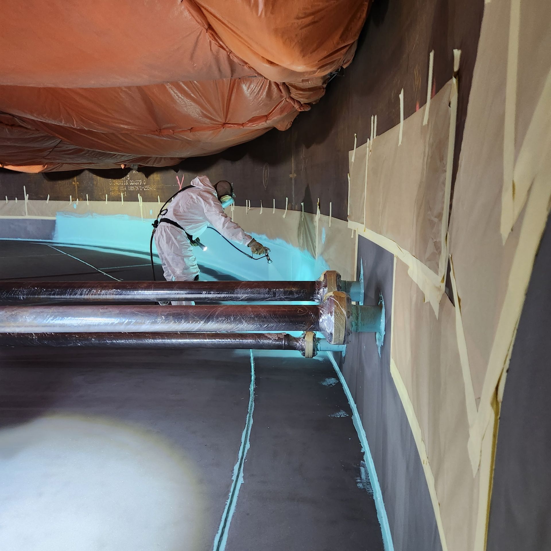 Technician applying internal coating during tank painting process, ensuring corrosion resistance inside the tank