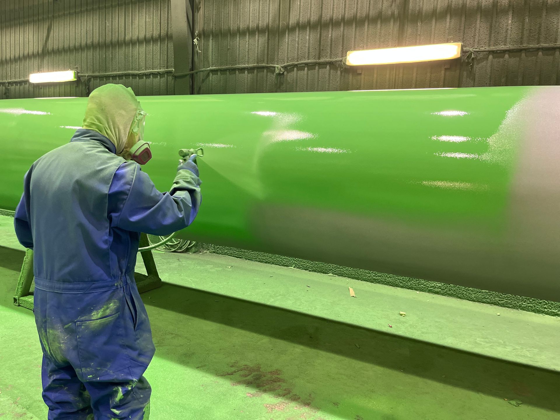Worker conducting detailed green coating process post-blast cleaning in controlled environment