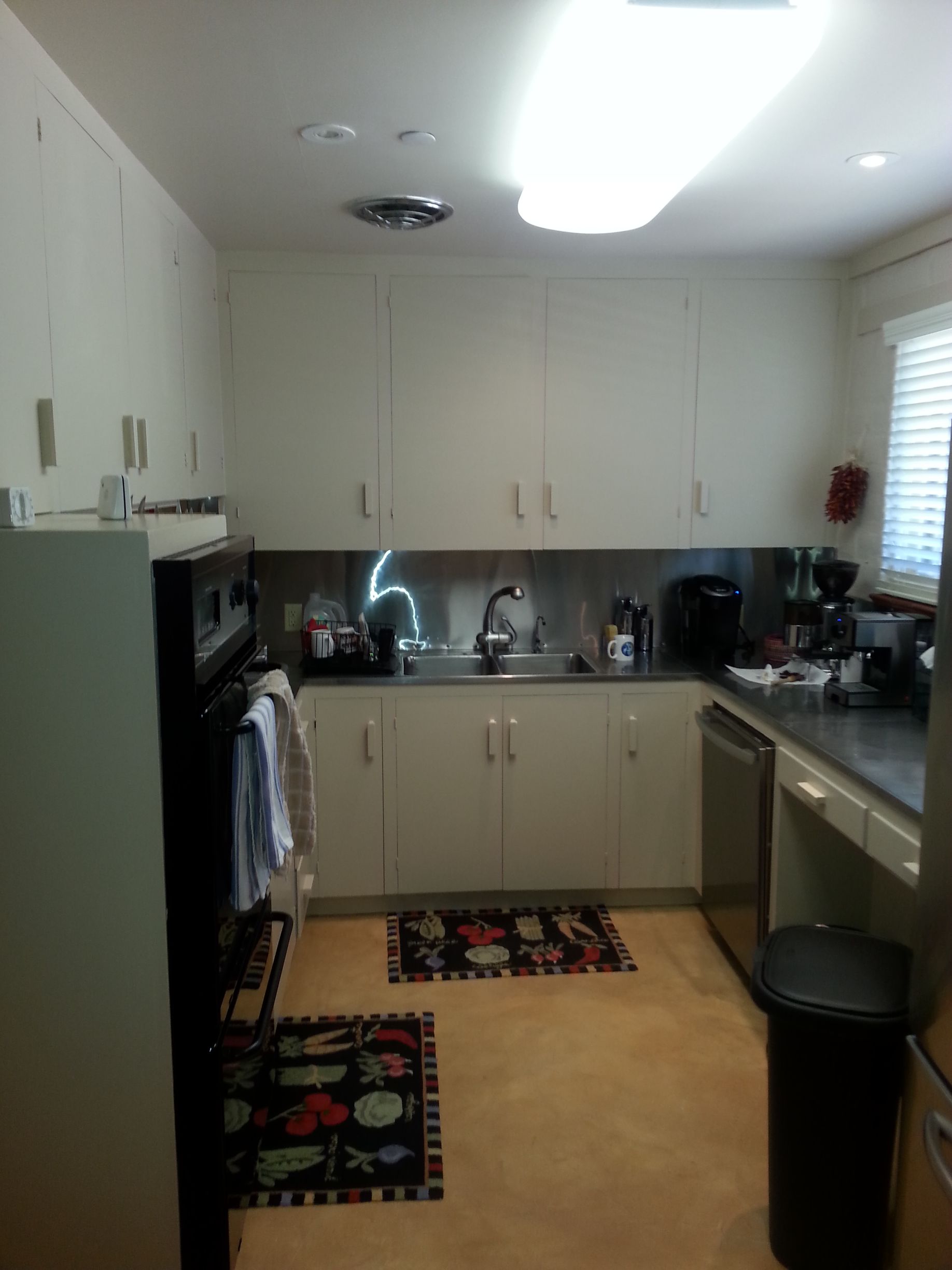 Kitchen with white cabinets, stainless steel backsplash, and appliances.