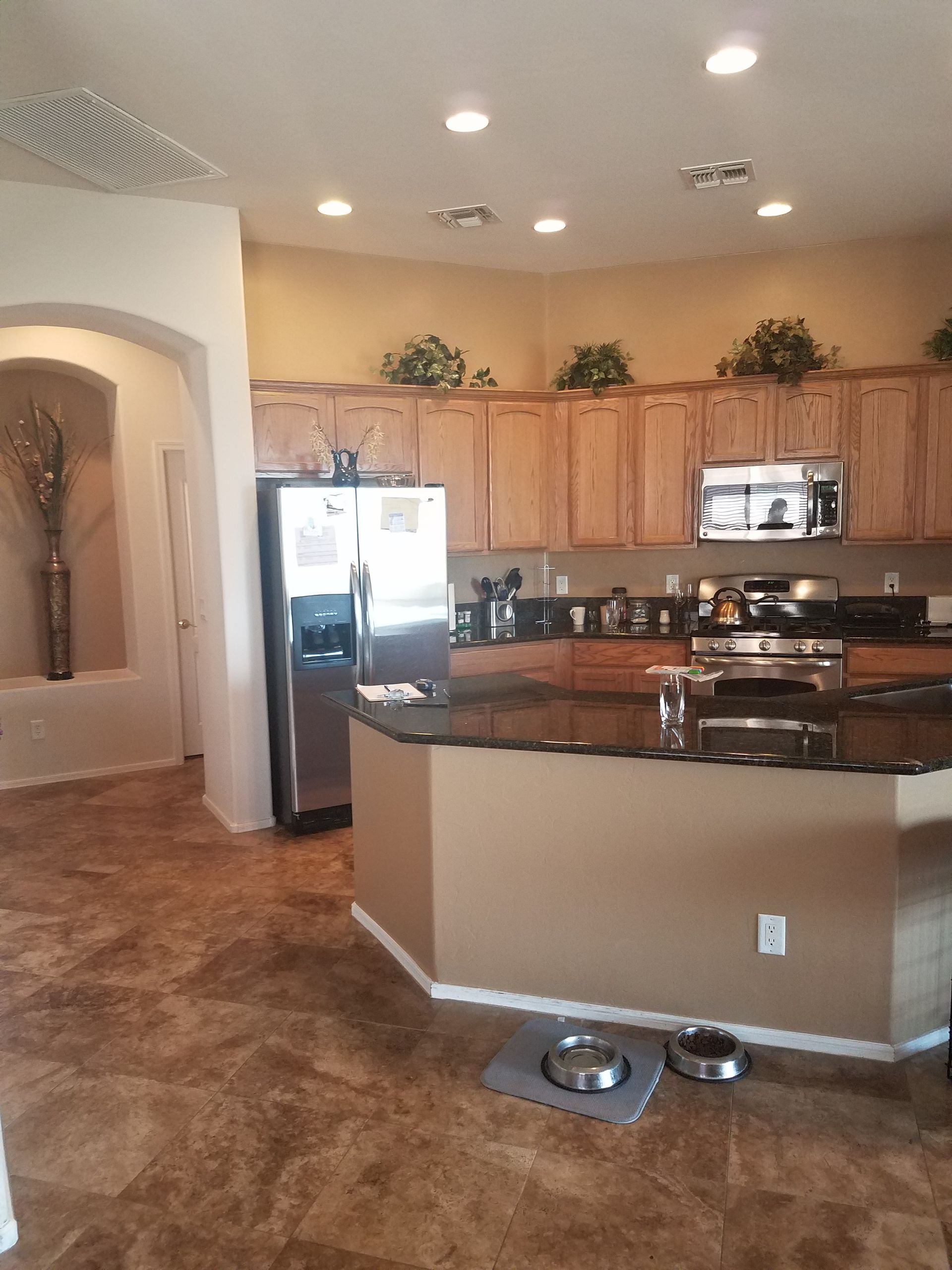 Kitchen with light brown cabinets, stainless steel appliances, dark countertop, and tiled floor.