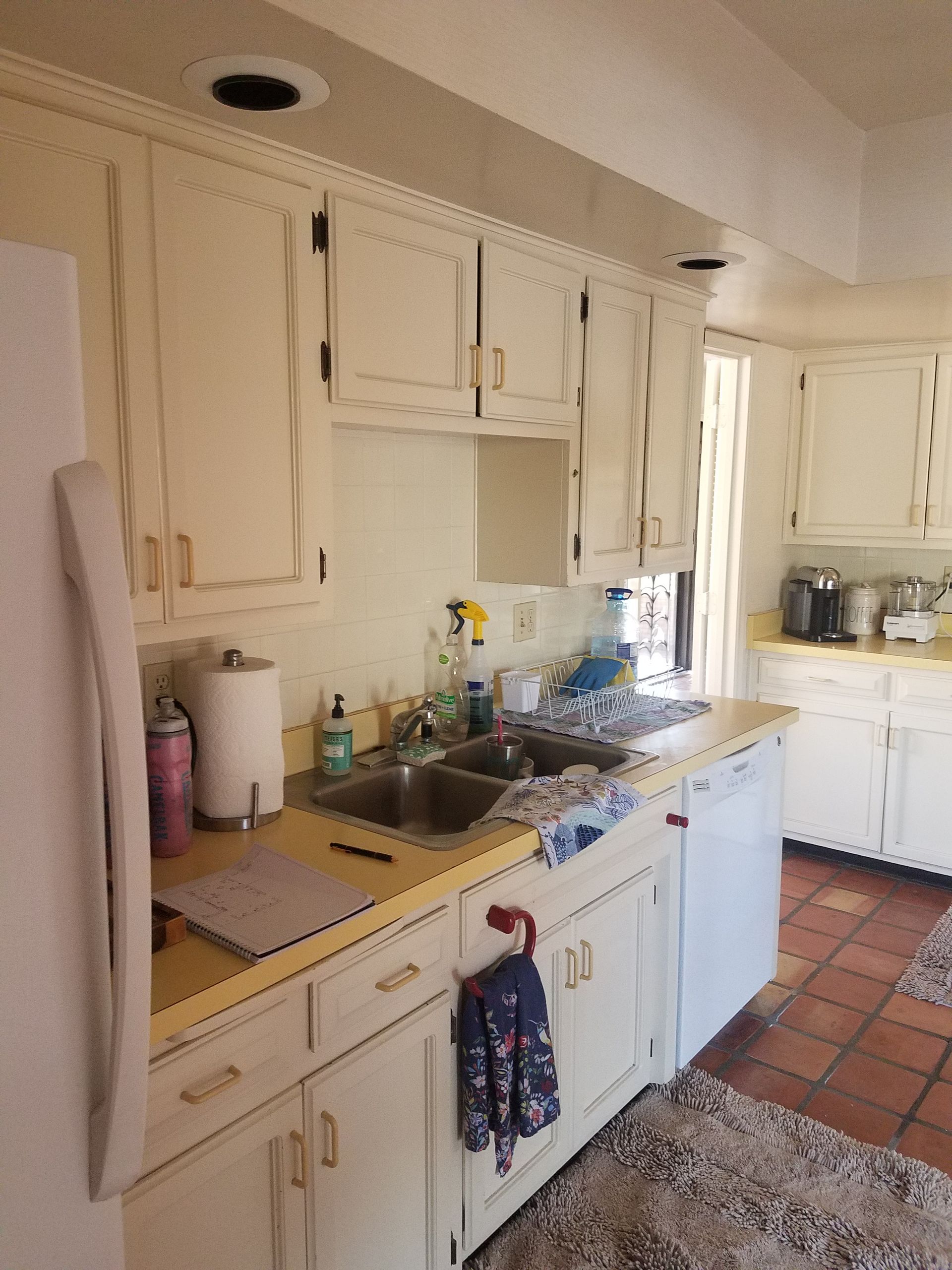 Kitchen with white cabinets, yellow countertop, and stainless steel sink.