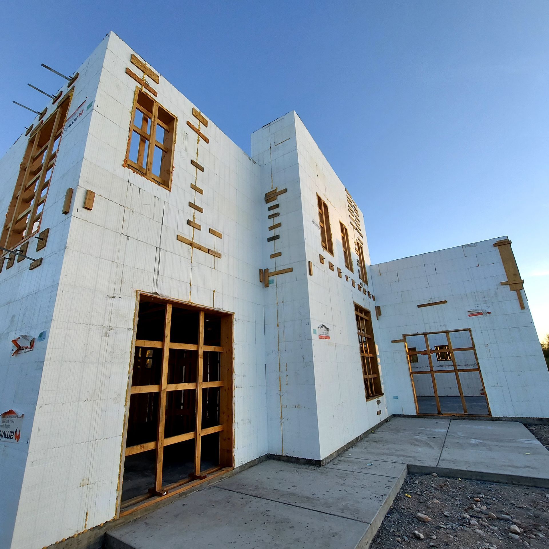 Building under construction with white insulation and wooden framing. Blue sky in background.