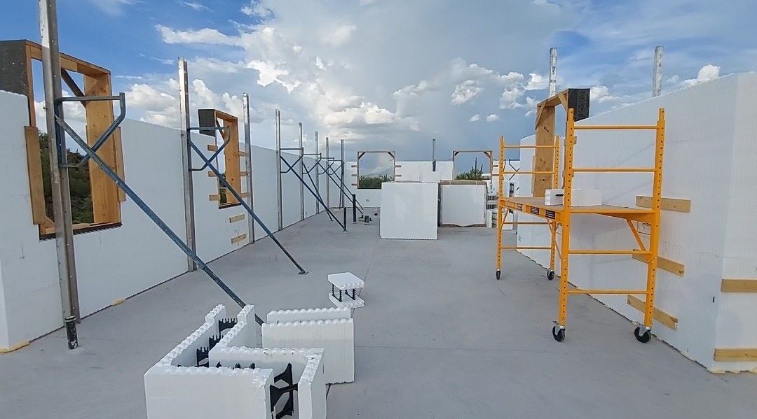 Construction site with white foam walls, scaffolding, and a cloudy sky.