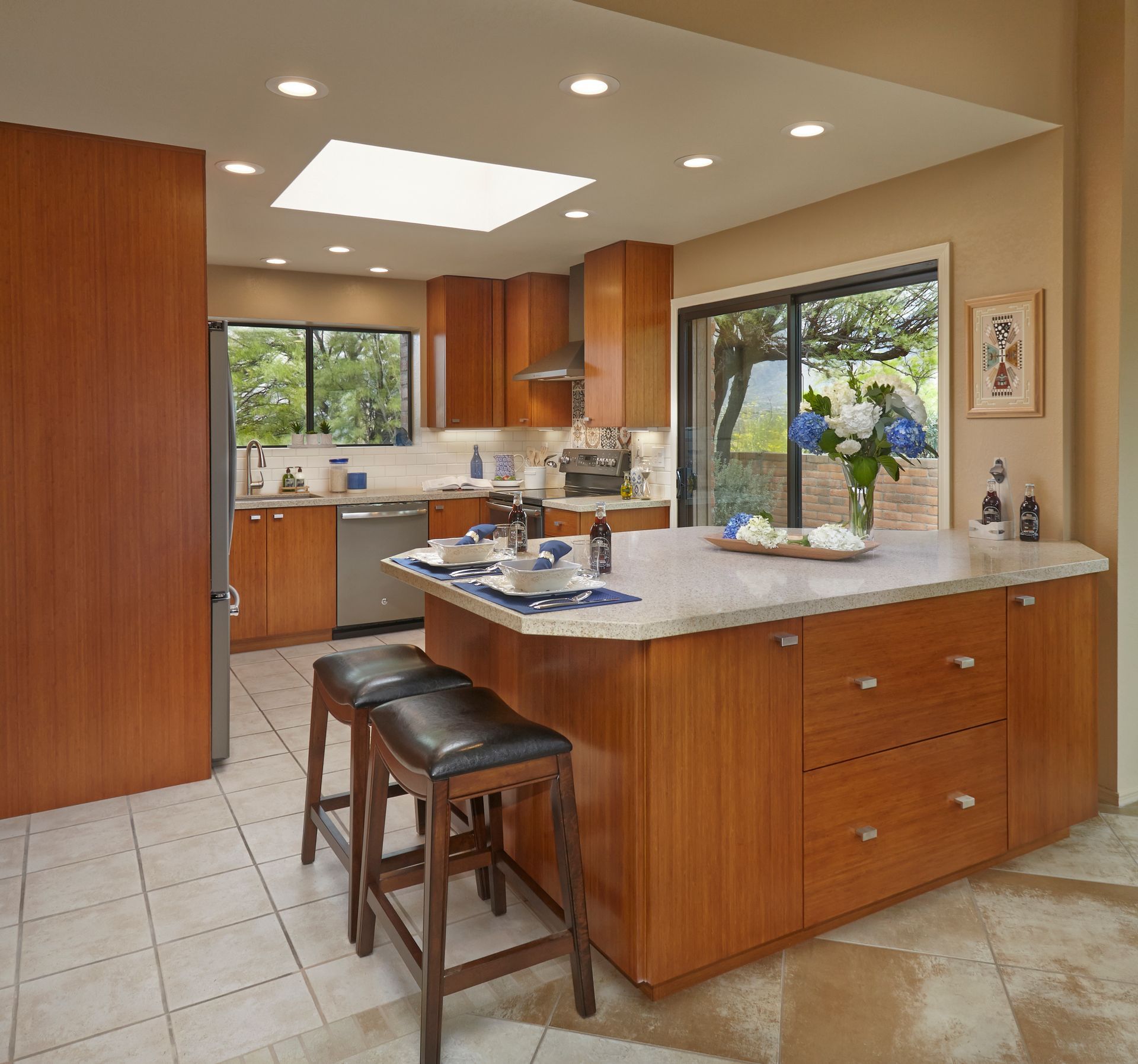 Modern kitchen with wood cabinets, island, and seating; window and skylight provide natural light.