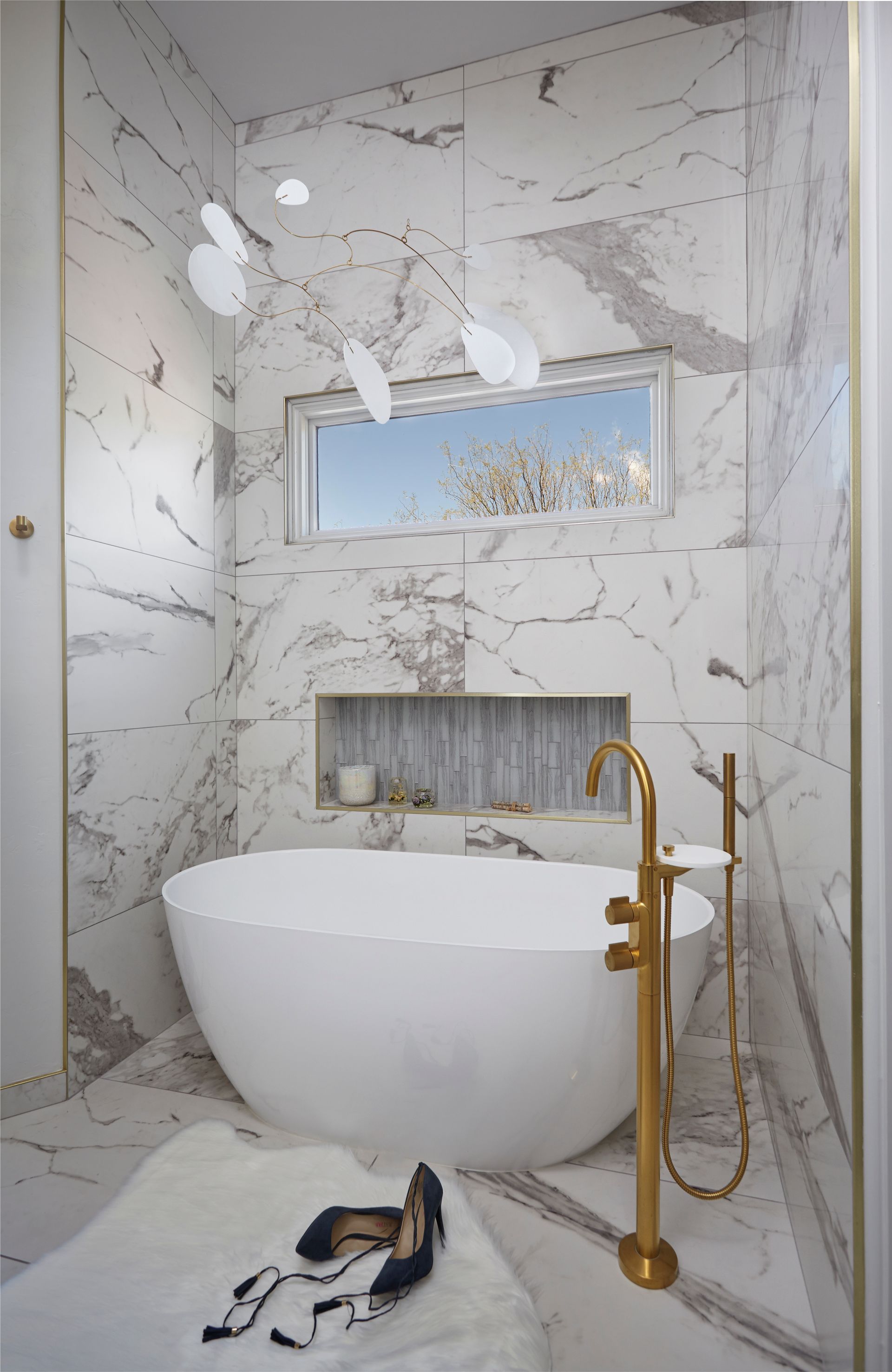 Luxurious bathroom with marble walls, a freestanding tub, and gold fixtures.