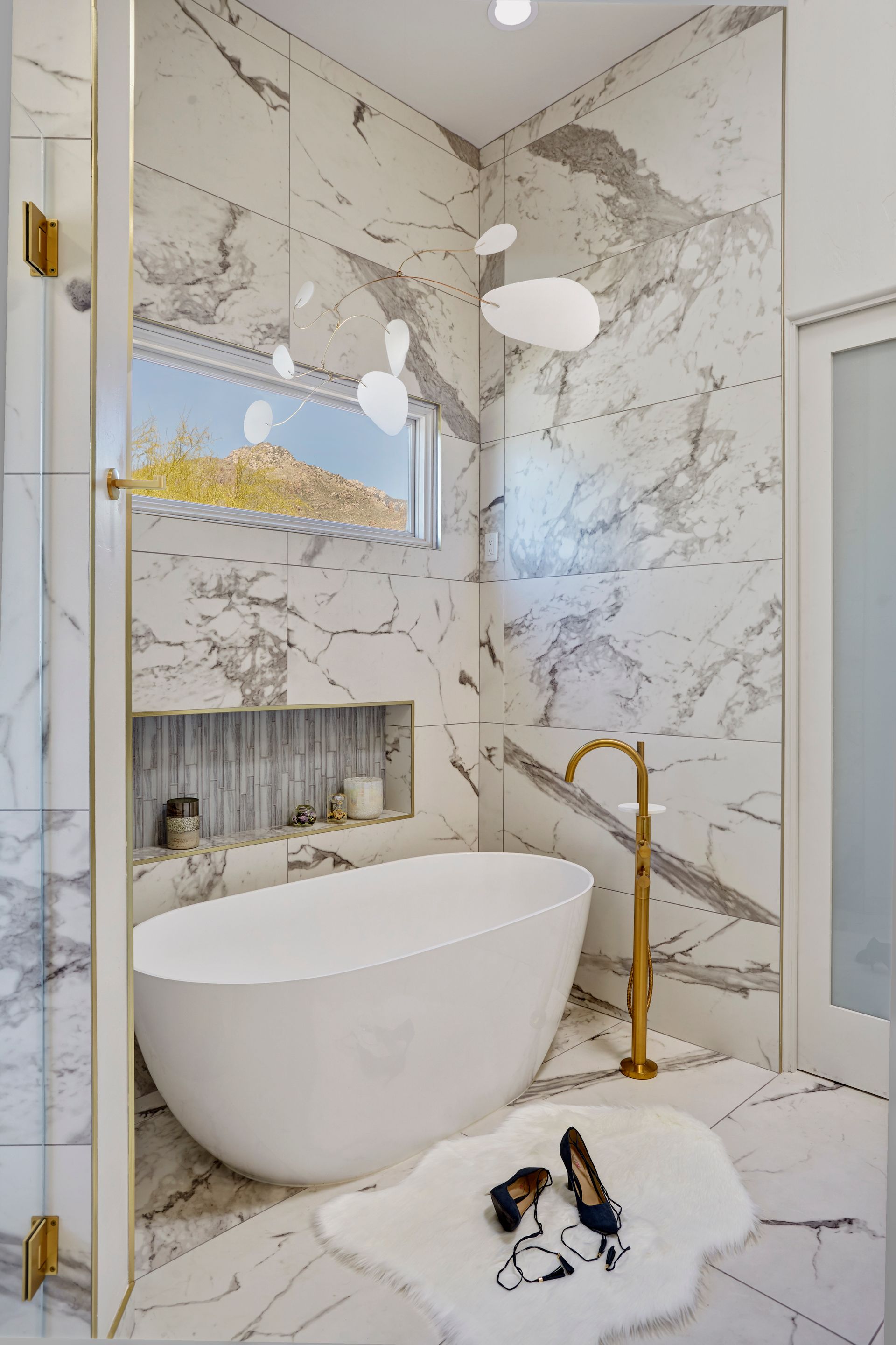 Luxurious marble bathroom with white soaking tub and gold fixtures.
