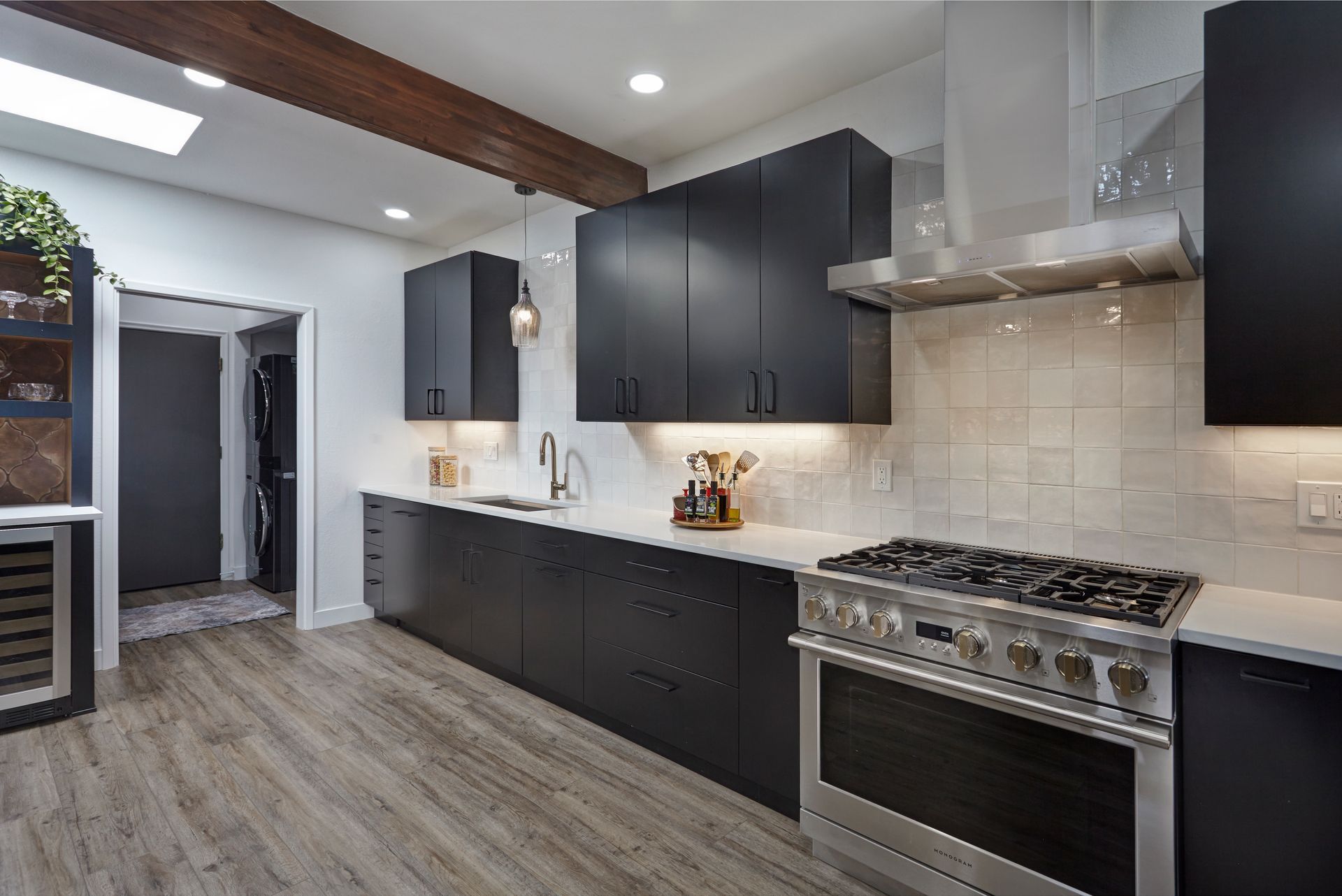 Modern kitchen with black cabinets, stainless steel appliances, and wood floors.