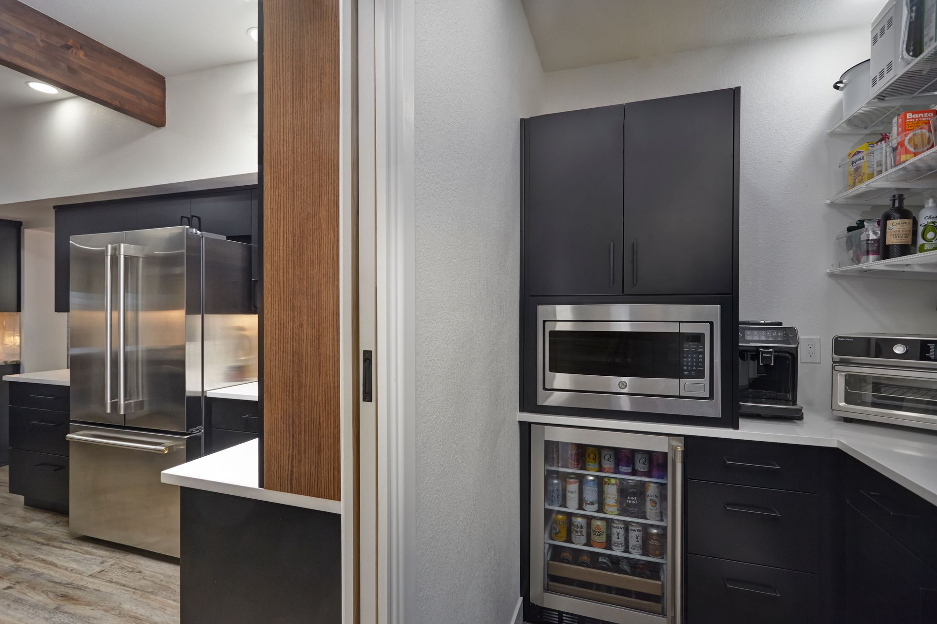 Modern kitchen with black cabinets, stainless steel appliances, and a beverage cooler.