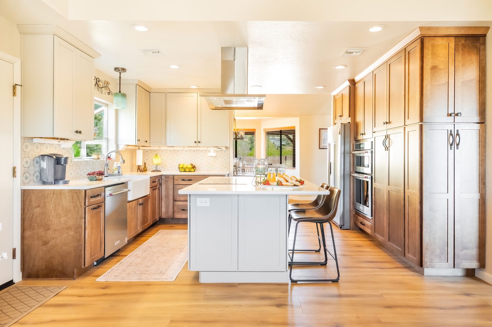Spacious kitchen with wood cabinets, white island, stainless steel appliances, and wood flooring.