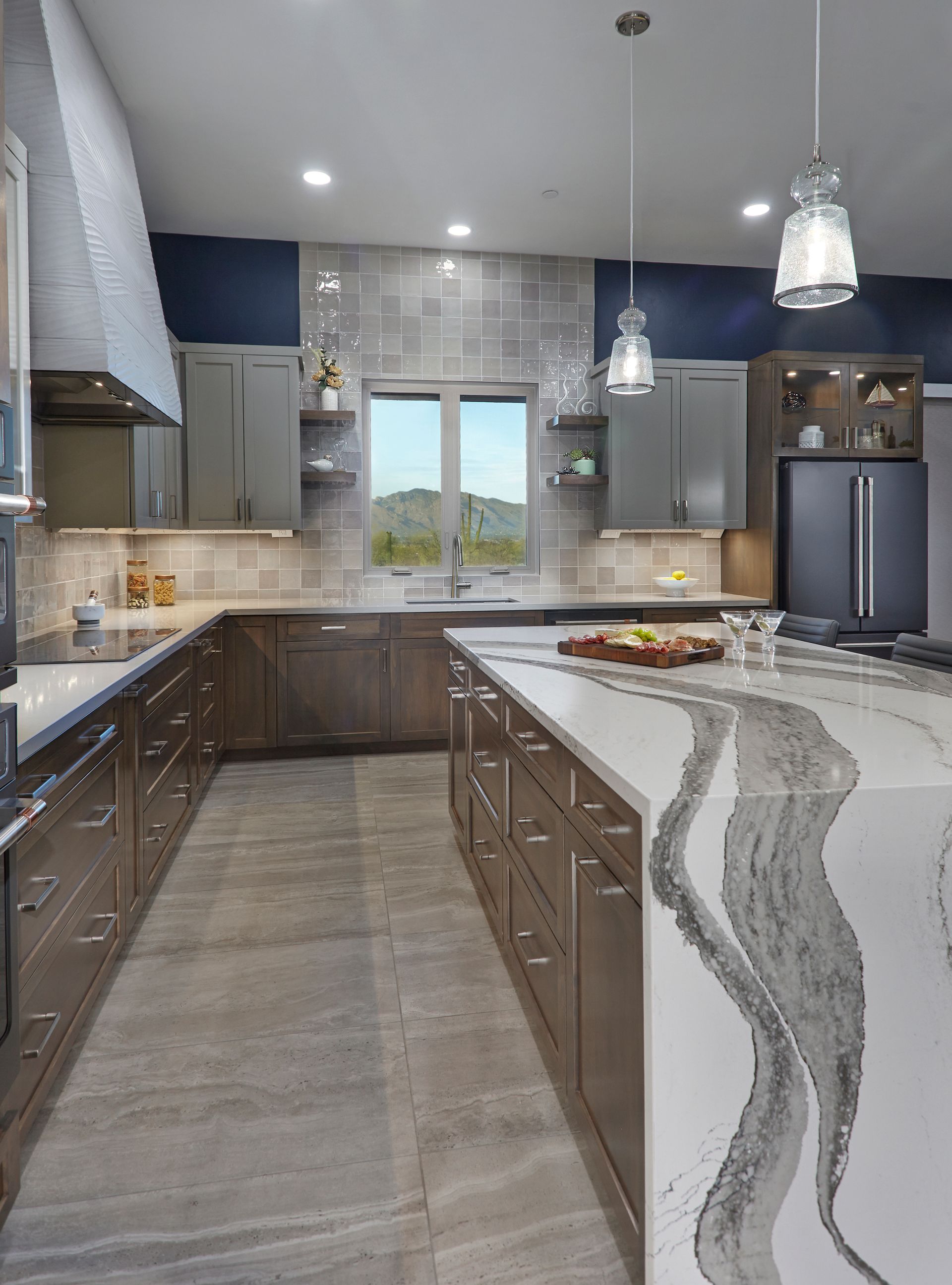 Modern kitchen with gray cabinets, large island with white countertop, and blue accent wall.