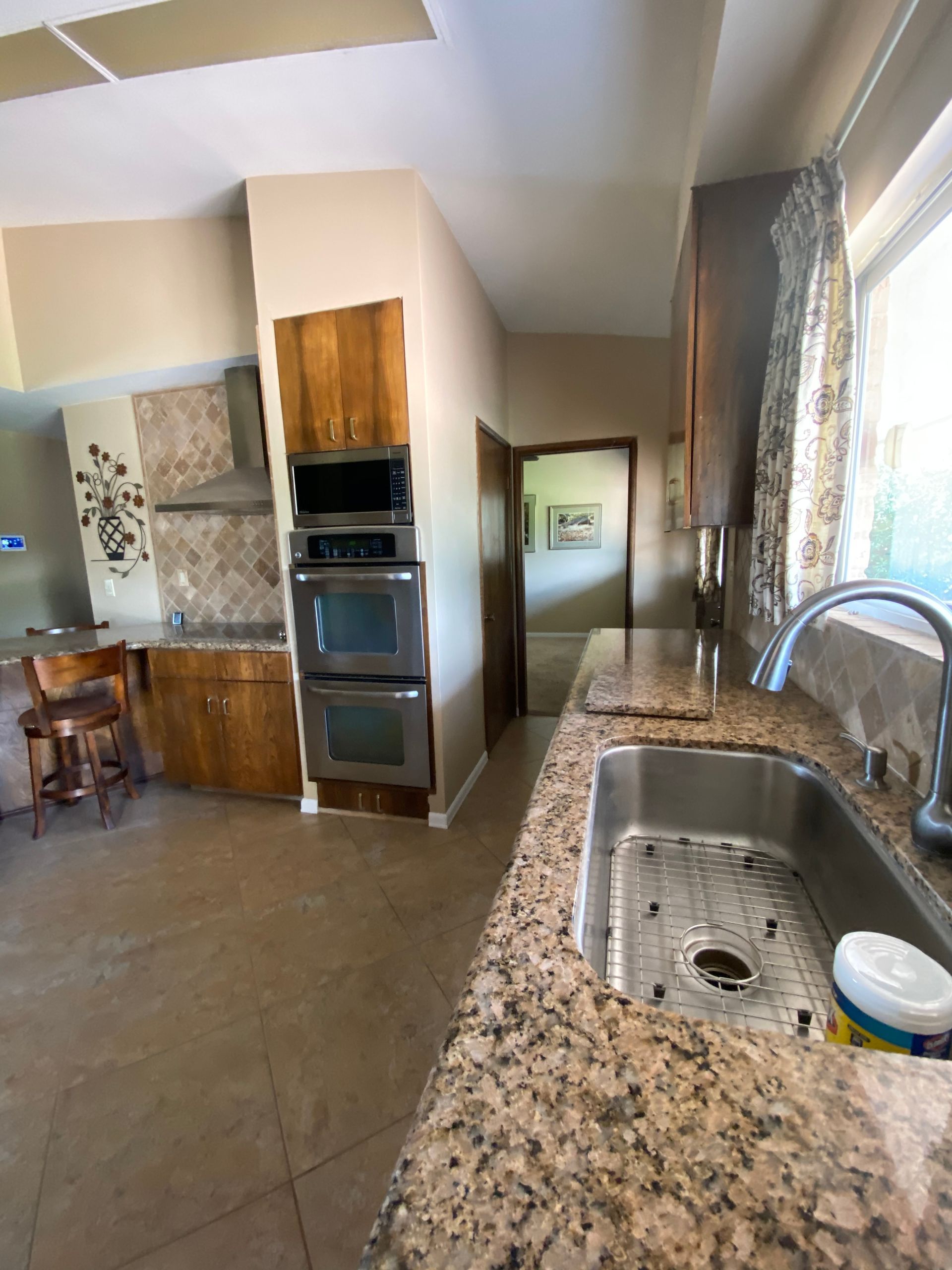 Kitchen with granite countertops, stainless steel sink, and built-in ovens.