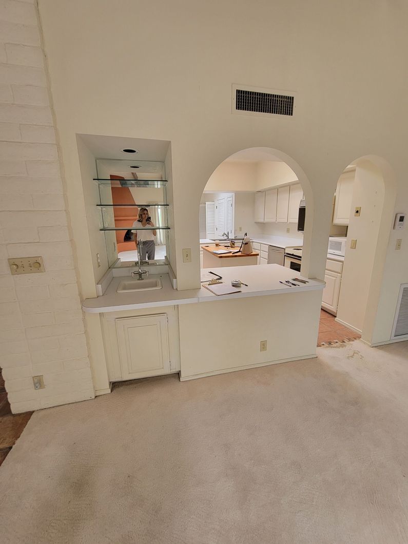 Interior with arched doorways. Kitchen in background, built-in bar with glass shelves and cabinet.