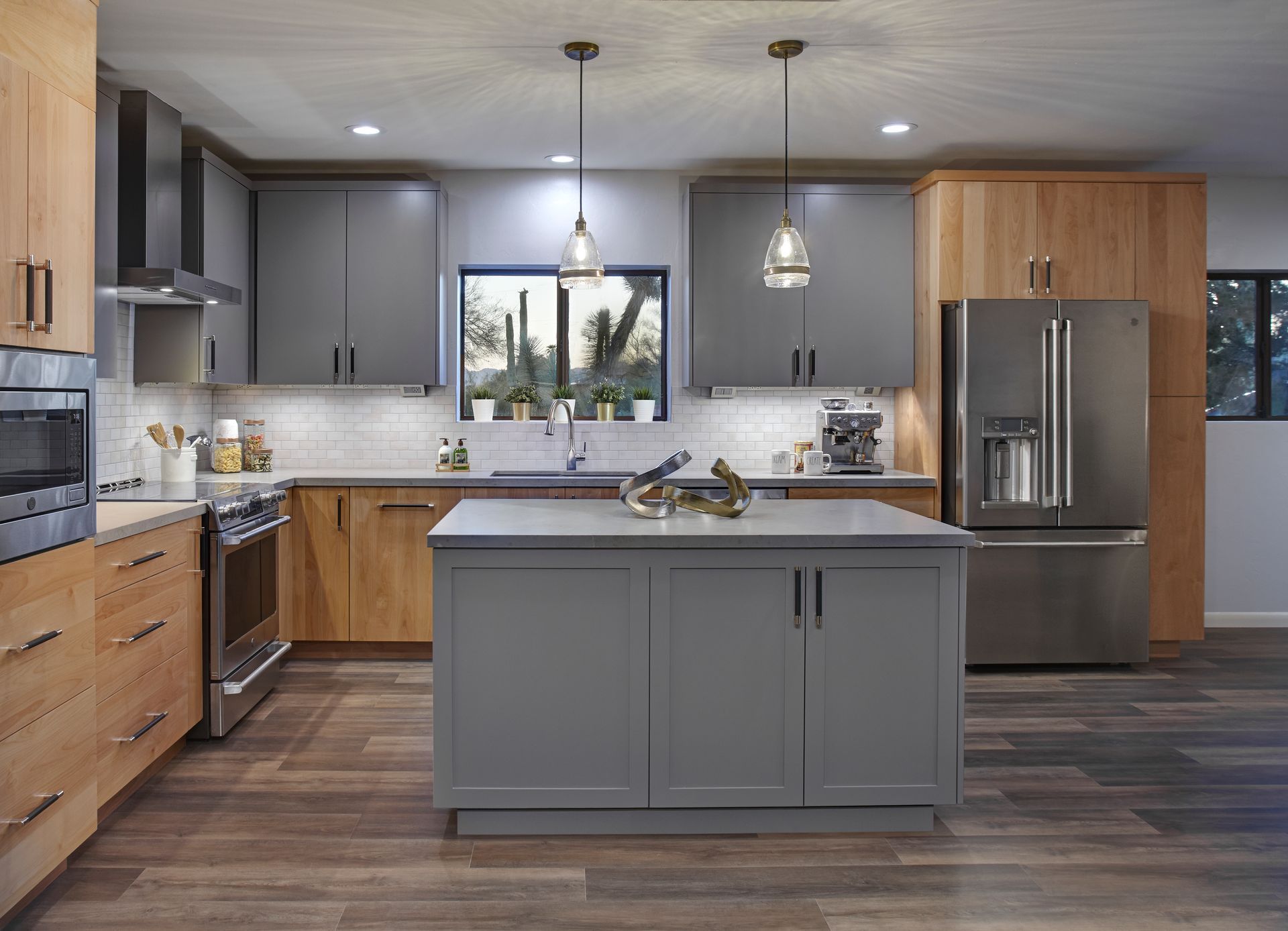 Modern kitchen with gray and wood cabinets, island, and stainless steel appliances.