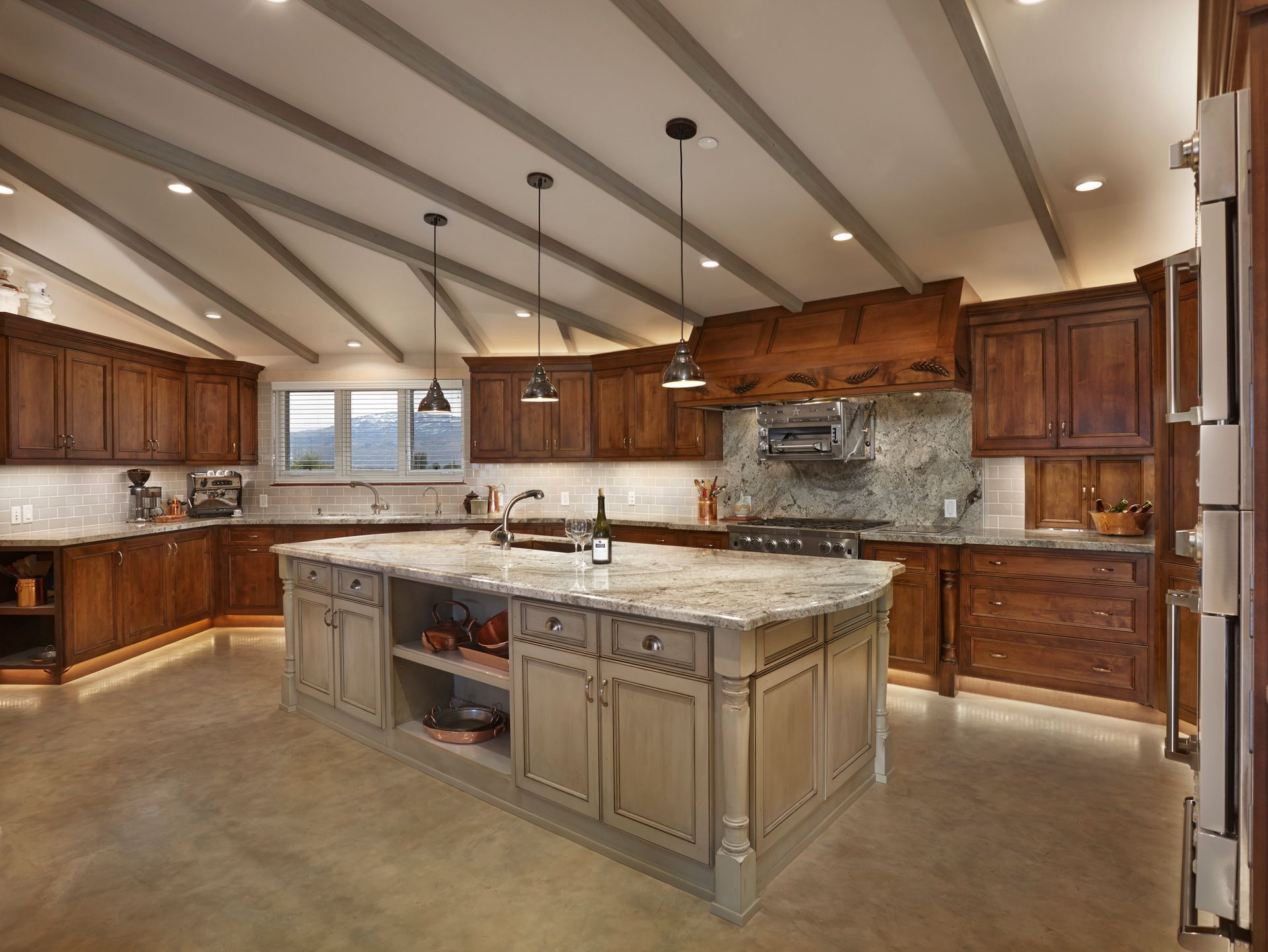 Spacious kitchen with wood cabinets, light-colored island, and angled ceiling with recessed lighting.