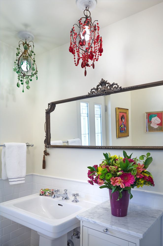 Bathroom with ornate mirror, vibrant floral arrangement, and colorful beaded light fixtures.