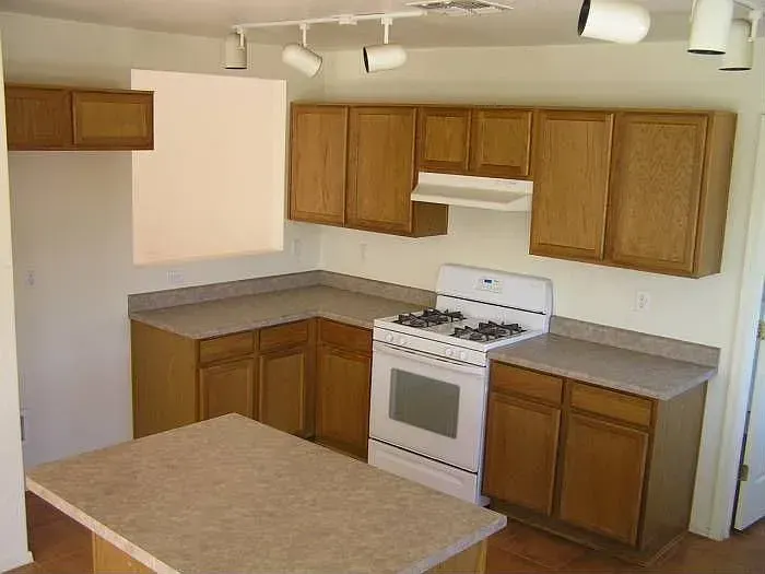 Kitchen with light wood cabinets, white stove, countertops, and island.