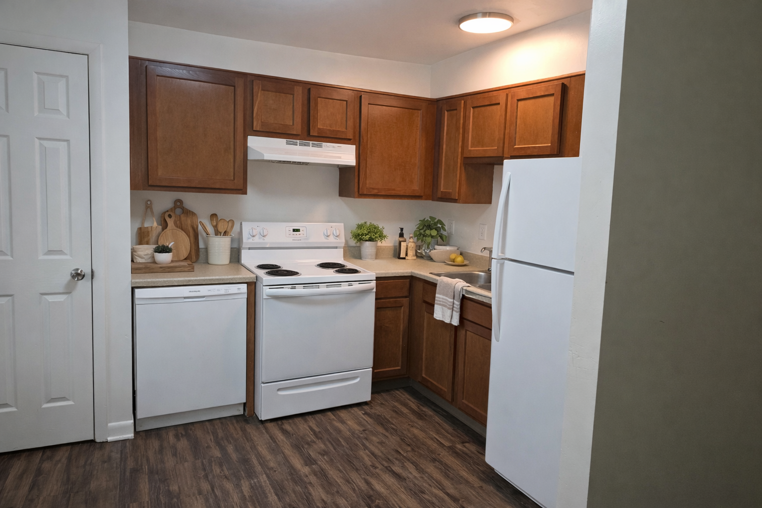 Small kitchen with wood cabinets, white appliances, and a white refrigerator under warm ceiling light