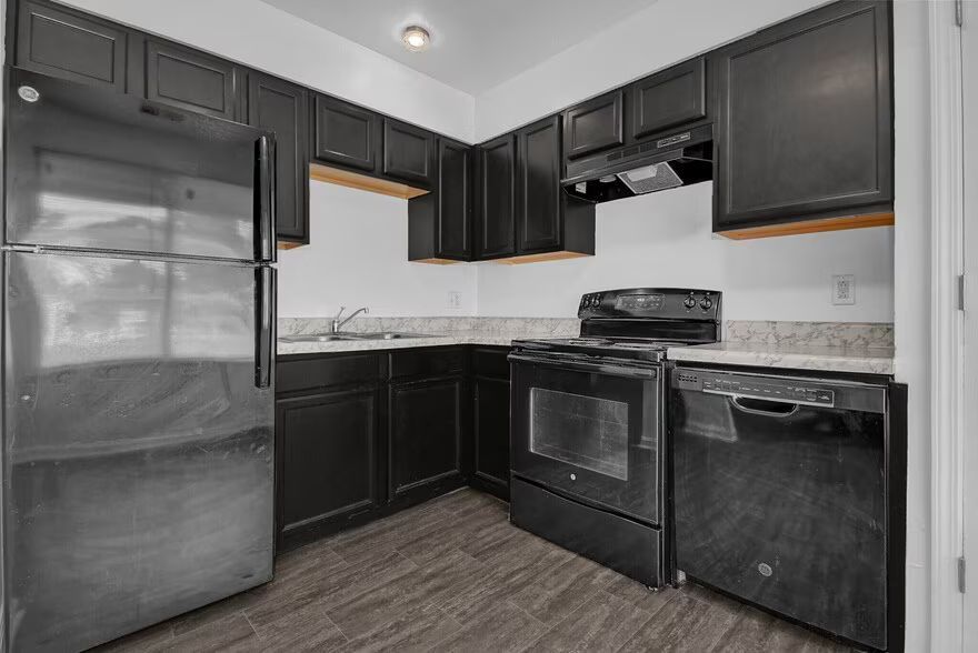 Compact kitchen with black appliances and cabinets, white countertops, and gray flooring