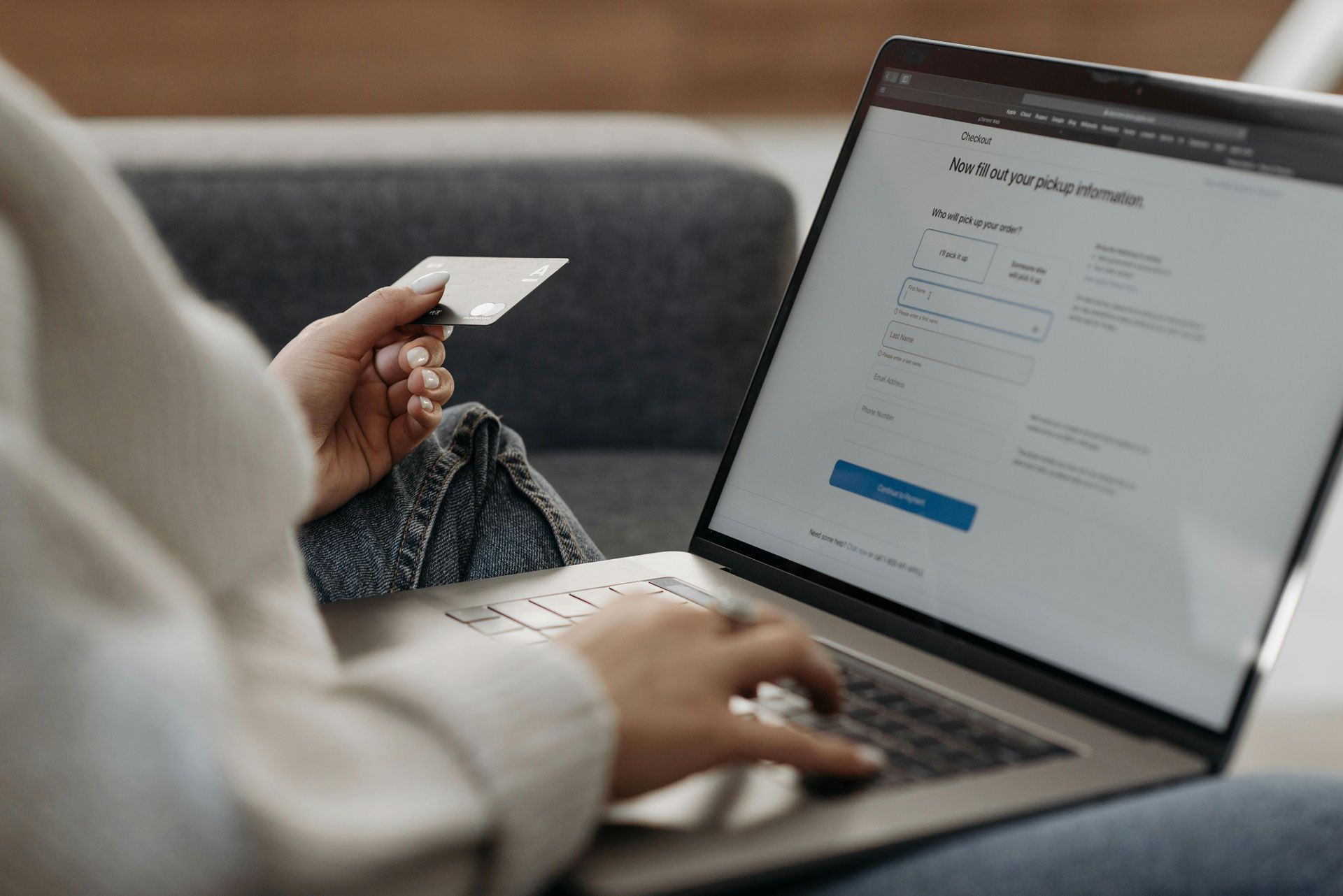 Personne utilisant un ordinateur portable, tenant une carte de crédit, remplissant un formulaire en ligne.