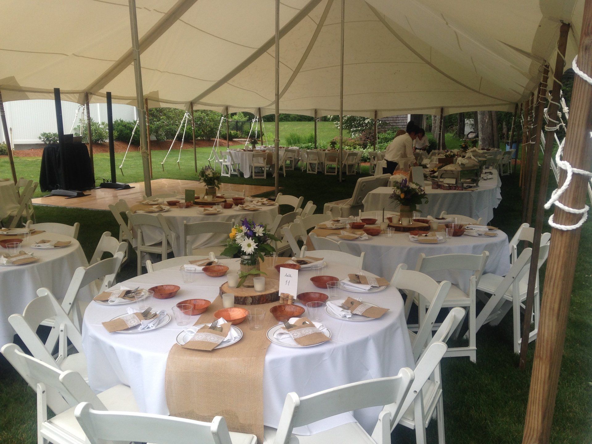 Tables and chairs are set up under a tent for a wedding reception