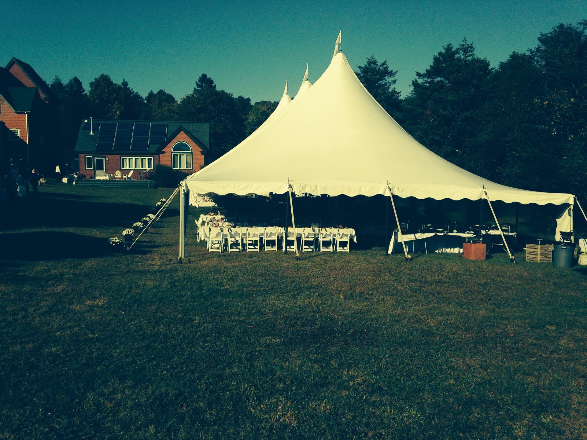 A large white tent sits in the middle of a grassy field
