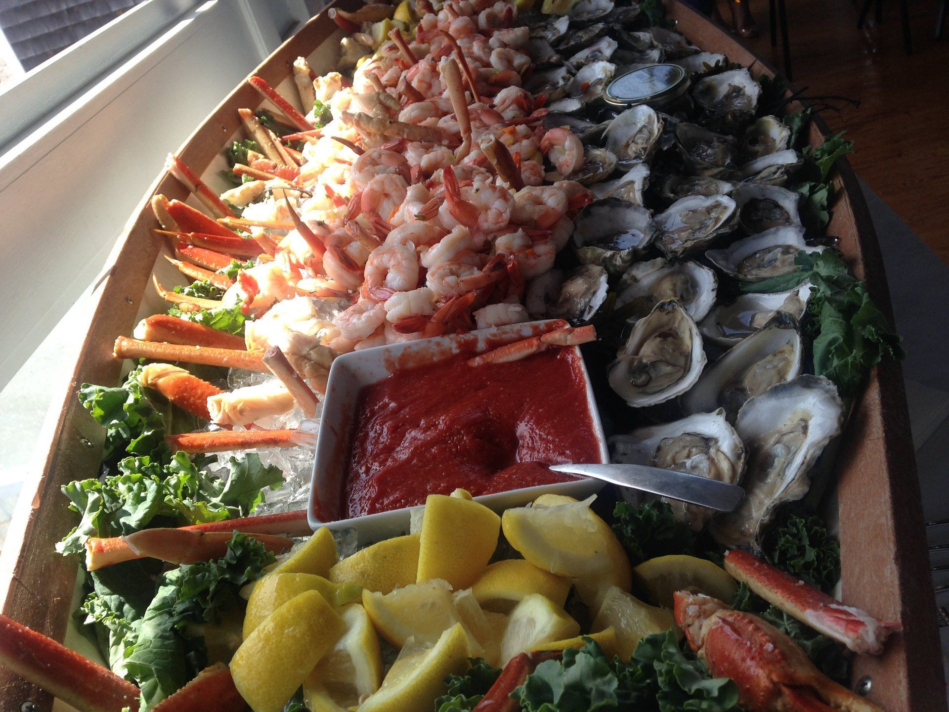 A boat filled with seafood including shrimp oysters and crab legs