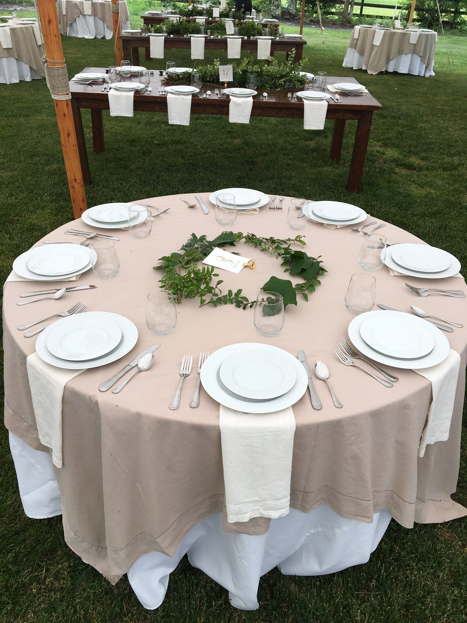 A round table with plates, silverware, and a wreath on top of it