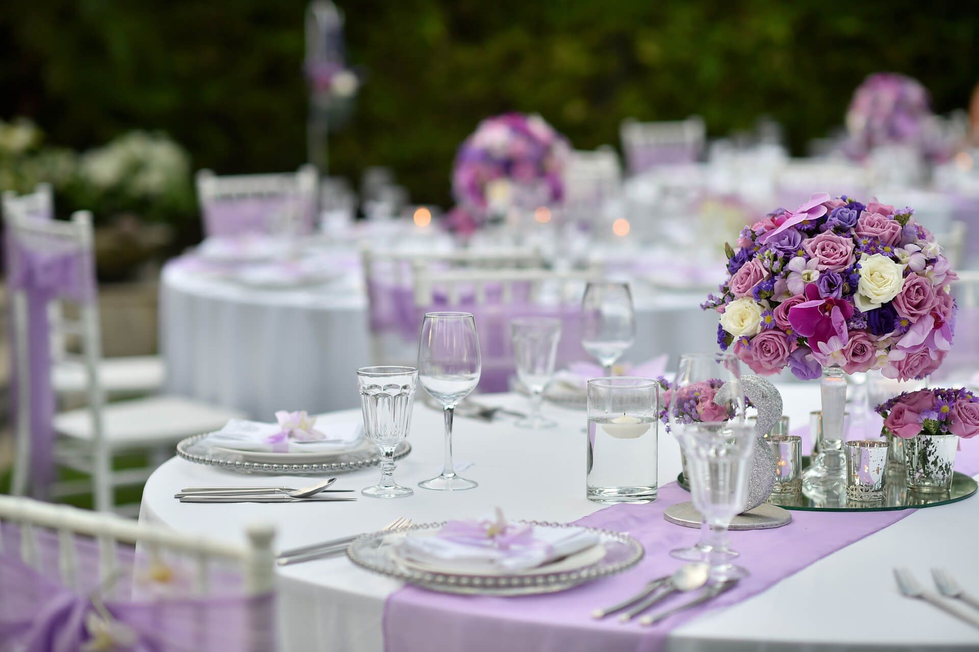 A table set for a wedding reception with purple flowers on it