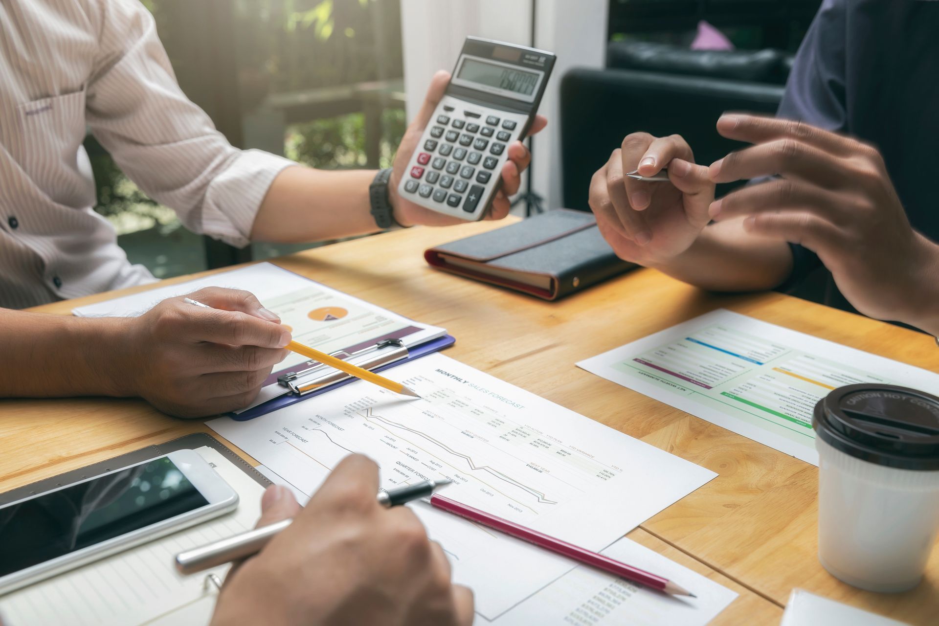Calculator, pen, notebook, and keyboard on a desk with financial reports.