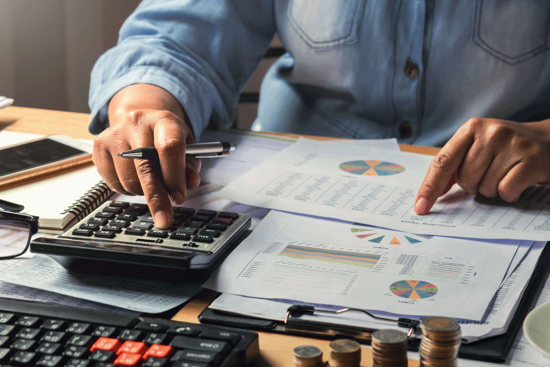 Person calculating finances with calculator and papers.