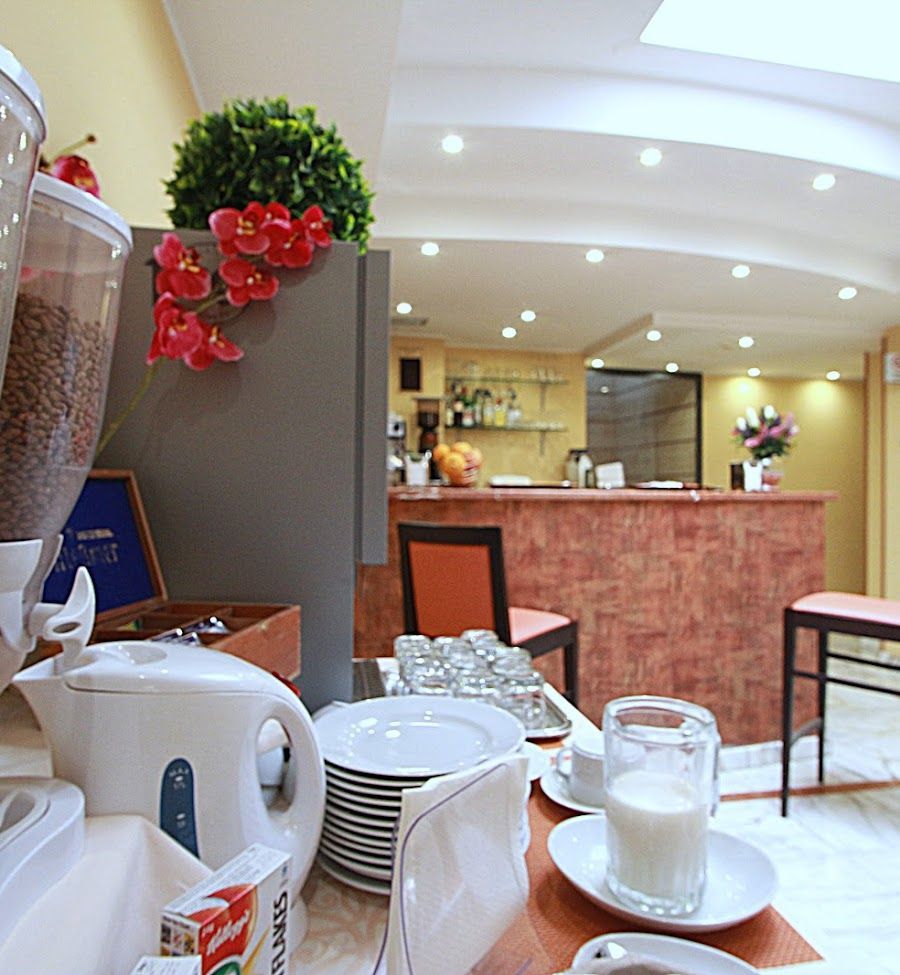 Colazione a buffet con cereali, bollitore e latte, vicino a un bar.