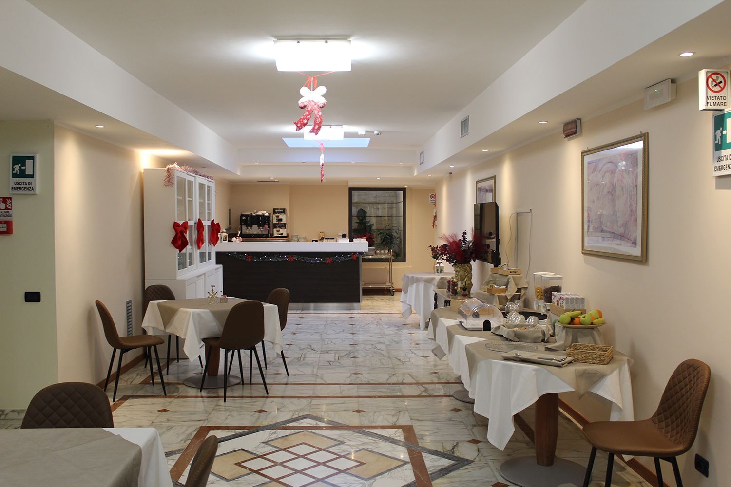 Area colazione dell'hotel con tavoli, buffet e bar.