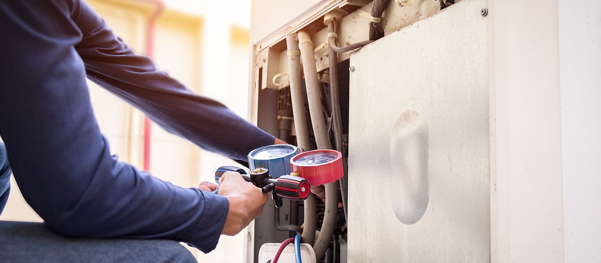 Technician using a red multimeter to inspect wiring inside an electrical panel