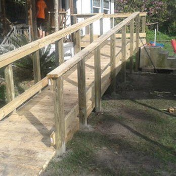 A wooden ramp leading to a house with a railing.