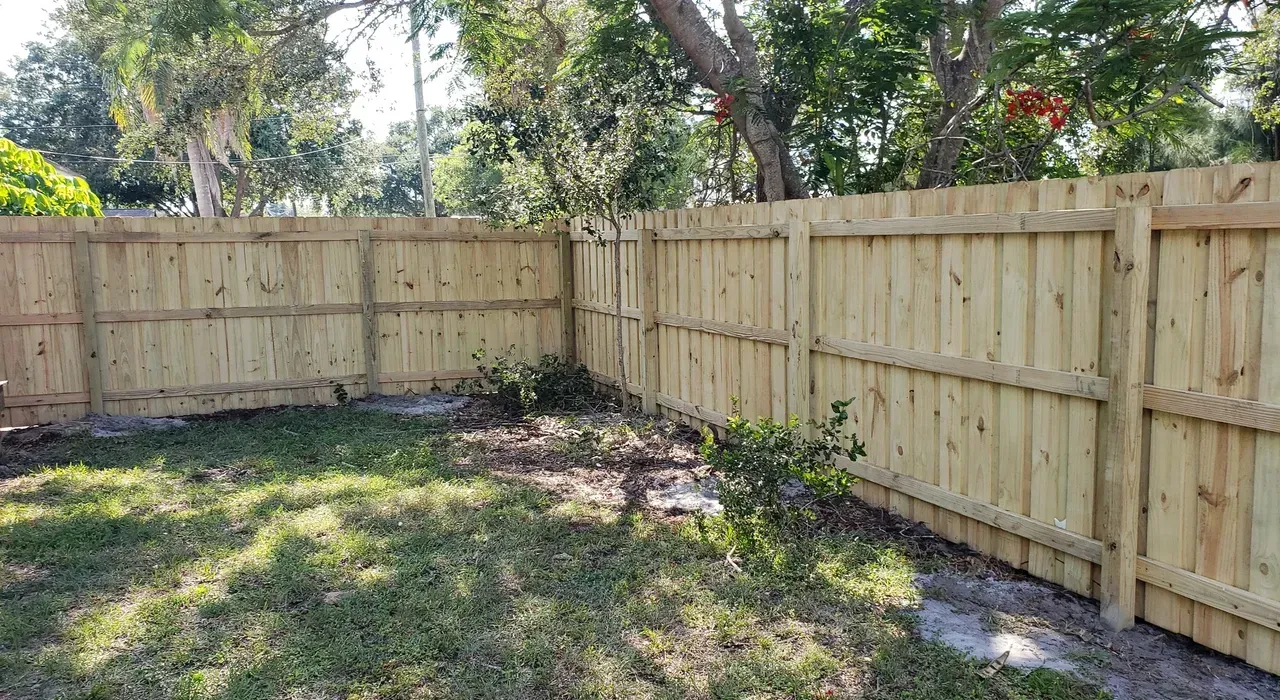 A wooden fence is in the backyard of a house.