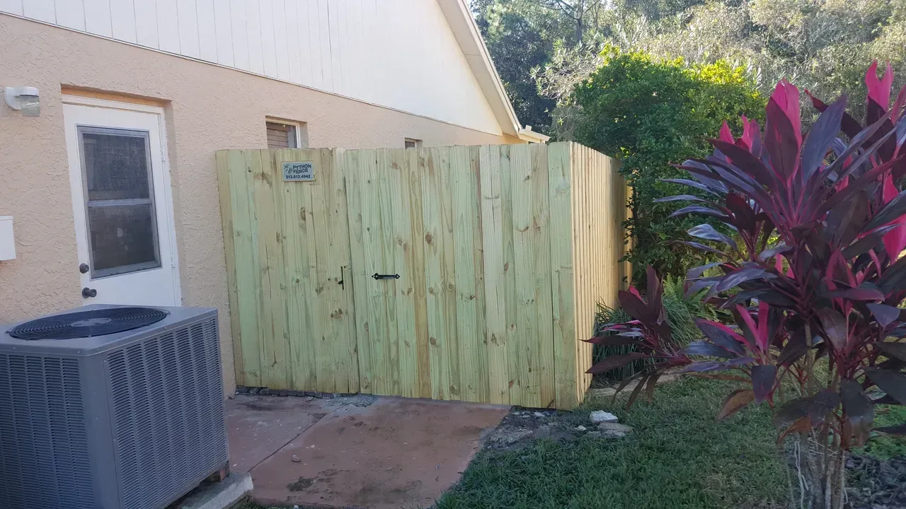 A wooden fence is in the backyard of a house.