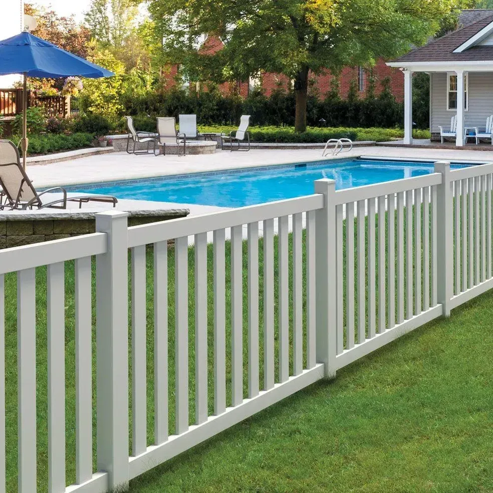 A white fence surrounds a swimming pool in a backyard