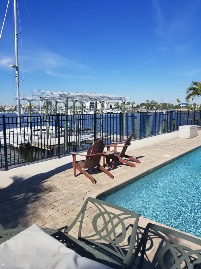 A swimming pool with chairs and a dock in the background.