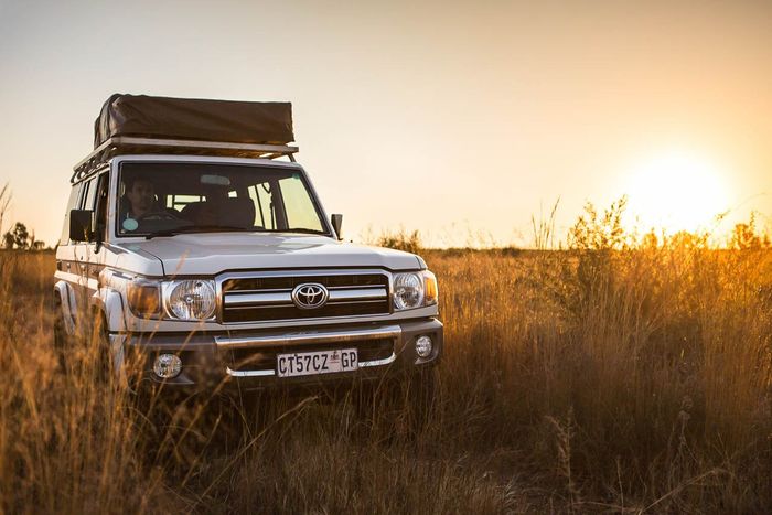 Toyota safari 4x4  vehicle in the african bush with a tent installed on it's roof