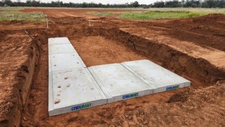 Concrete foundation slabs laid in a dug-out construction site with reddish soil