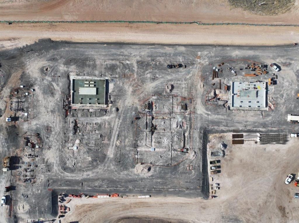 Aerial view of a large burned construction site with two damaged structures and scorched ground